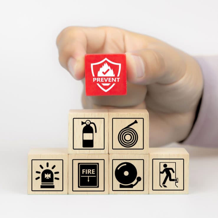wooden toy blocks stacked with a red fire prevention icon being held by hand
