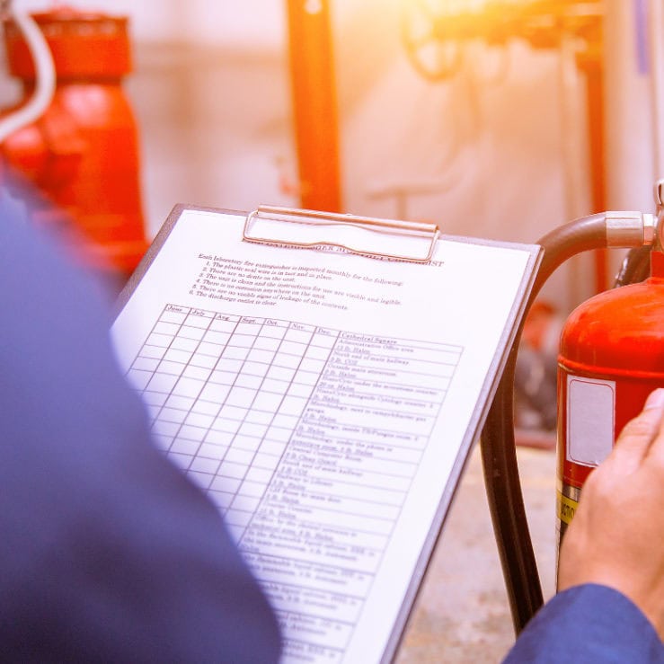 Someone completing a fire prevention risk assessment for a fire extinguisher